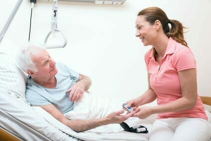 Pflegerin bei der Blutzuckermessung beim Patienten Krankenschwester im Krankenhaus