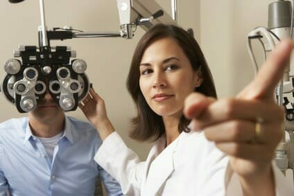 Female Optician In Surgery Giving Man Eye Test Female Optician In Surgery Giving Man Eye Test
